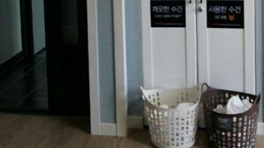 Una habitación con una puerta cerrada, una cesta blanca y una cesta marrón sobre el suelo.