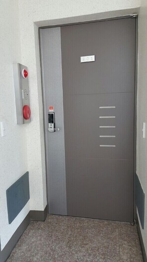 A door with a number plate, a fire alarm, and a security intercom. - Namu Guesthouse & Pension - Hostel (Yeosu)