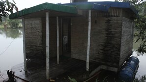 A small, rustic wooden structure with a green roof, situated by a body of water.