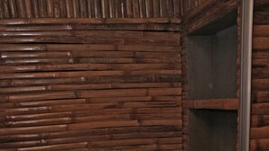 A small, wooden-paneled bathroom with a toilet and a shelf.