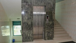 An elevator with a digital display, a staircase, and a window with blinds. - Saint Martin Resort (Cox's Bazar)