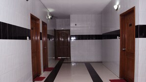 A hallway with white and black tiled walls, wooden doors, and a red carpet. - Saint Martin Resort (Cox's Bazar)