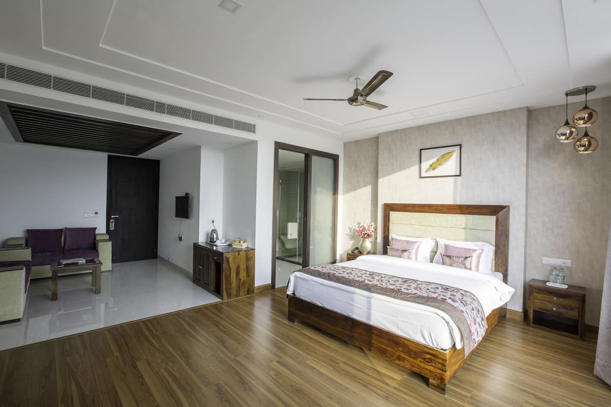 Un dormitorio moderno con una cama grande, un ventilador de techo y suelo de madera.