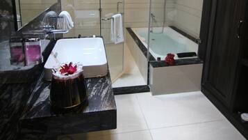 Un baño moderno con ducha de vidrio, una bañera y un tocador con lavamanos y espejo.