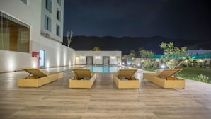 A poolside area with lounge chairs and a swimming pool at night. - Brahma Horizon Hotel & Spa – Pushkar (Pushkar)
