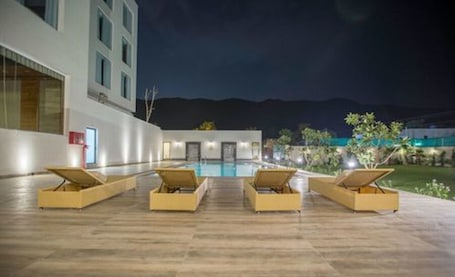 Una piscina al aire libre, sillones reclinables de piscina