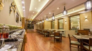 A restaurant with wooden flooring, tables, chairs, and hanging light fixtures. - Brahma Horizon Hotel & Spa – Pushkar (Pushkar)