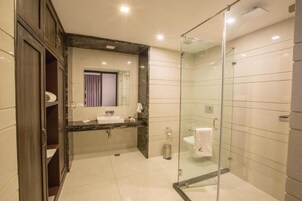 Un bagno moderno con cabina doccia in vetro, lavabo su piano in marmo e uno specchio grande.