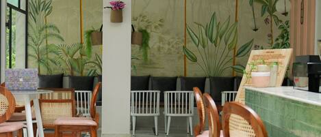 A restaurant interior with wooden chairs, a marble floor, and a mural of palm trees on the wall.