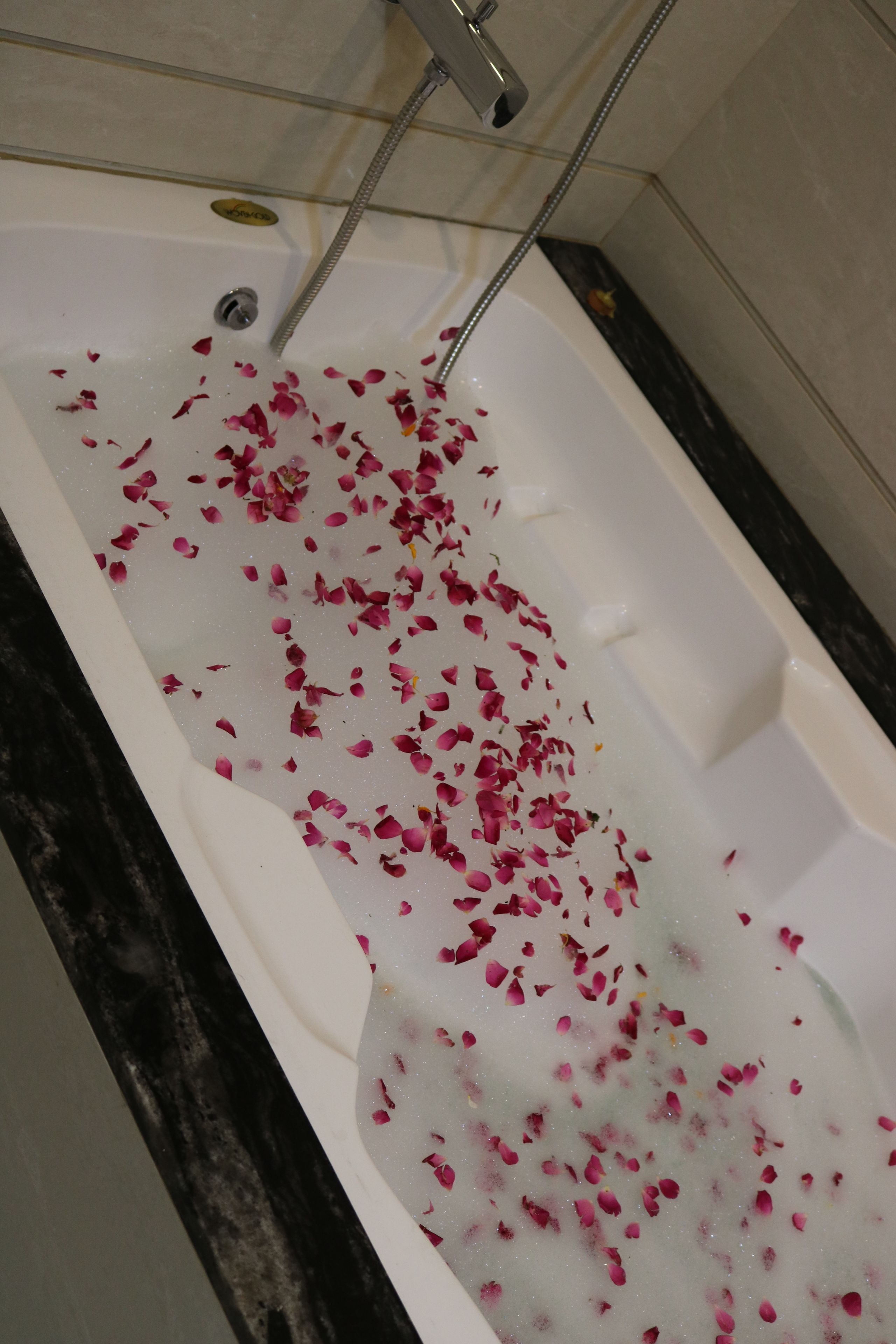 A bathtub filled with water and rose petals.