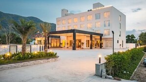 A modern hotel with a covered entrance, a landscaped garden, and a mountainous backdrop. - Brahma Horizon Hotel & Spa – Pushkar (Pushkar)
