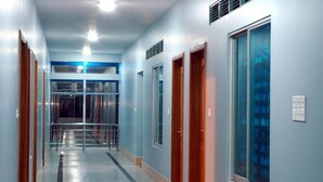 A hallway with a metal railing, wooden doors, and a large window. - Albatross Resort (Cox's Bazar)