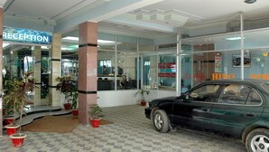 A reception area with a car parked outside, potted plants, and a tiled floor. - Albatross Resort (Cox's Bazar)