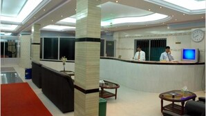 A hotel lobby with a reception desk, a clock, and a TV screen. - Albatross Resort (Cox's Bazar)
