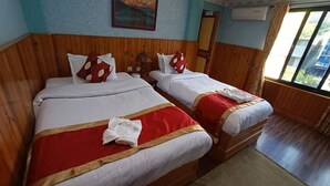 Two beds with red and white bedding, wooden headboards, and a window with a view. - Hotel Peace Palace (Baglung)