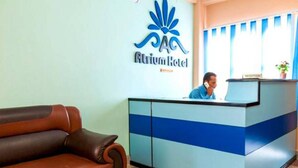 A reception desk with a logo for "Aritm Hotel" and a receptionist. - Hotel Atrium (Pokhara)