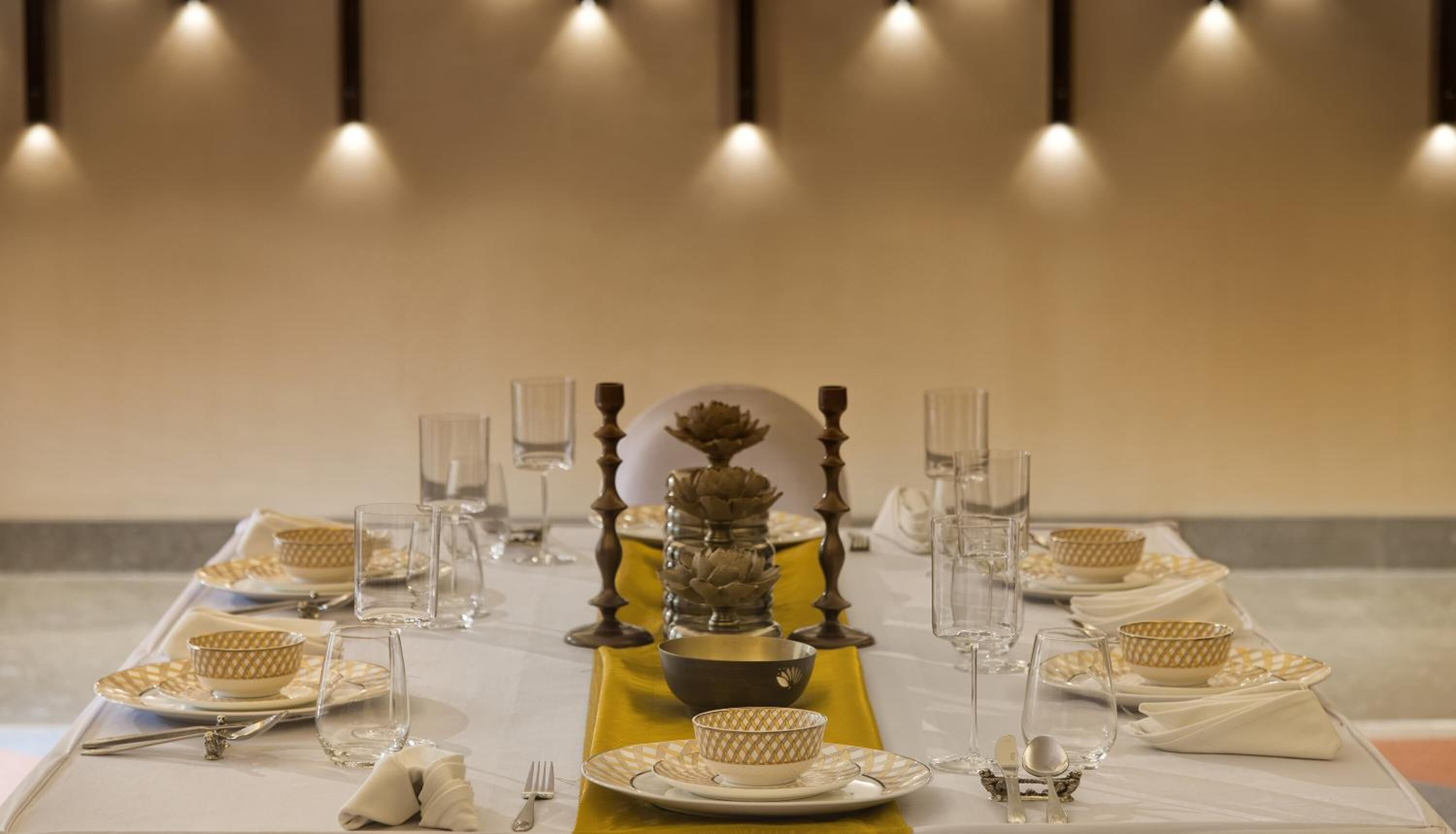 Une table à manger élégante, dressée avec soin et comprenant plusieurs couverts, notamment des assiettes, des bols, des verres et des couverts.