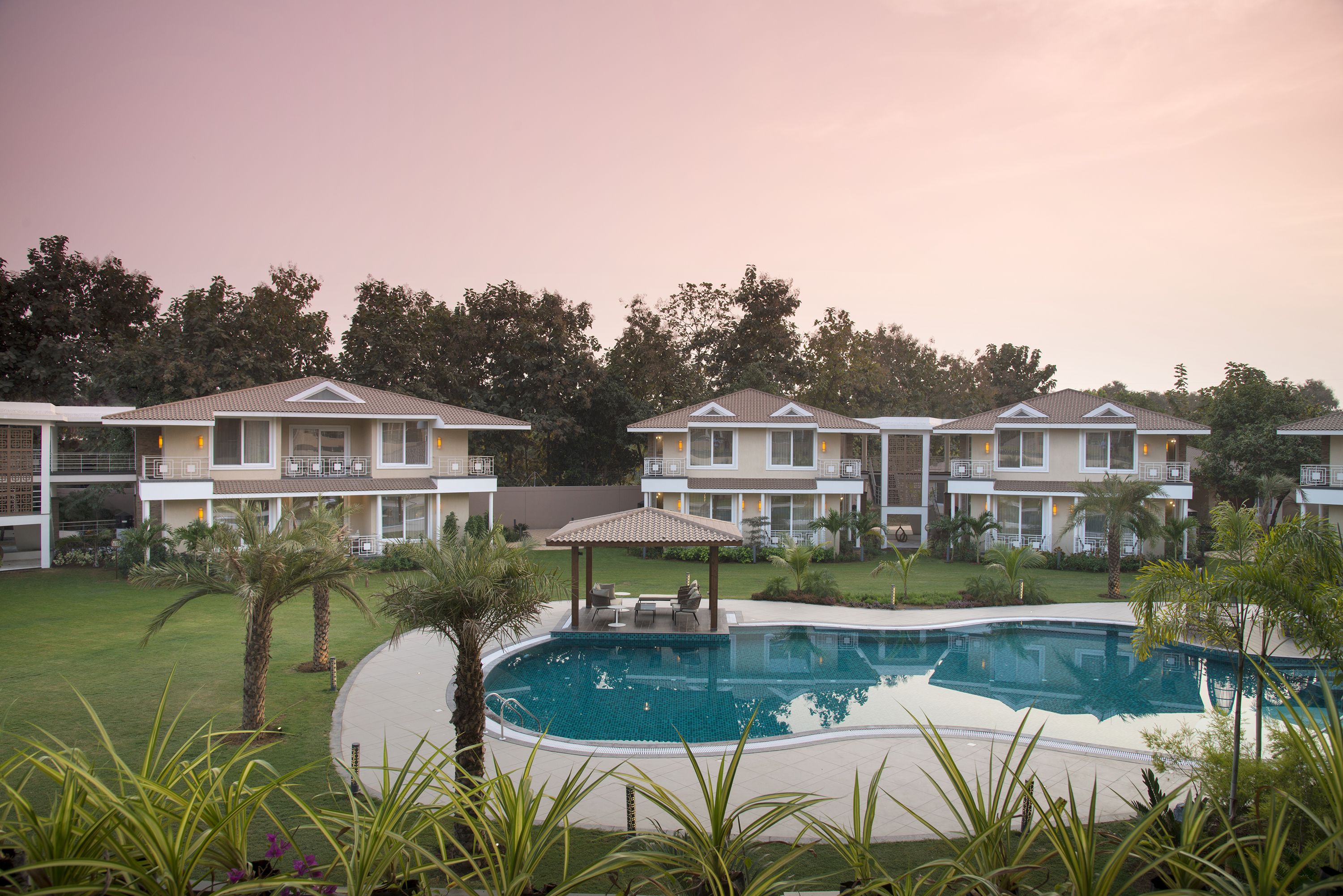 A resort with a swimming pool, multiple-story buildings, and a well-maintained lawn.