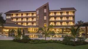 A multi-story hotel with a pool area and outdoor seating. - Kabir Hotel & Spa (Vadodara)