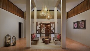 A spacious lobby with a high ceiling, a central seating area, and a decorative panel with leaf patterns. - Kabir Hotel & Spa (Vadodara)