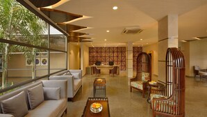 A modern lobby with a sofa, chairs, a coffee table, and a decorative wall. - Kabir Hotel & Spa (Vadodara)