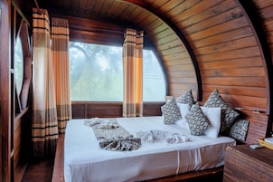 A cozy room with a curved wooden ceiling, a large bed with patterned pillows, and curtains.