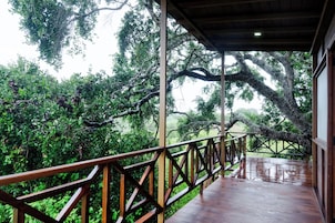 A wooden deck with a metal railing overlooking a lush green landscape.