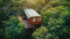 A treehouse with a wooden exterior and a metal roof, surrounded by dense forest. - Leopard Nest in Yala (Tissamaharama)
