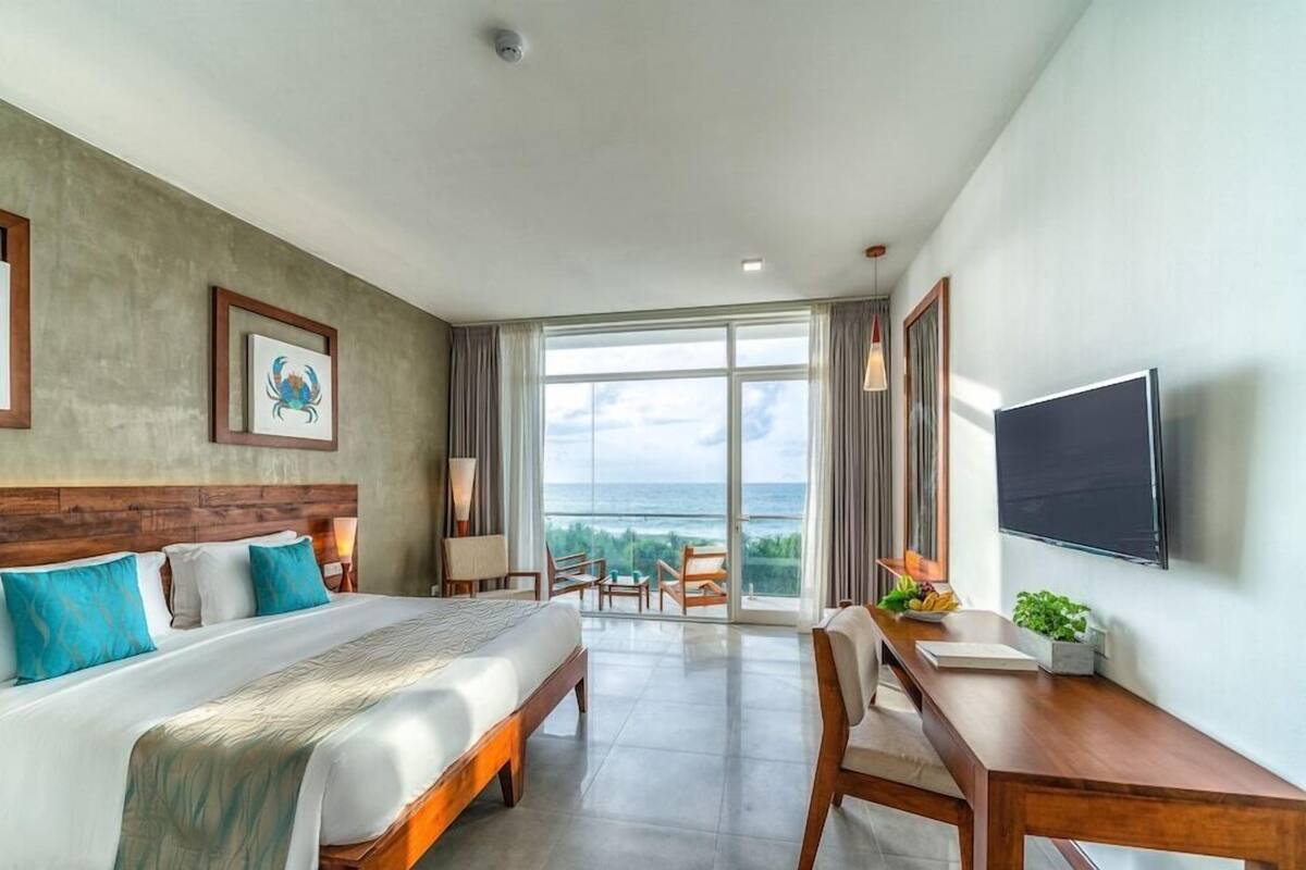 A hotel room with a bed, a desk, a TV, and a large window with a view.