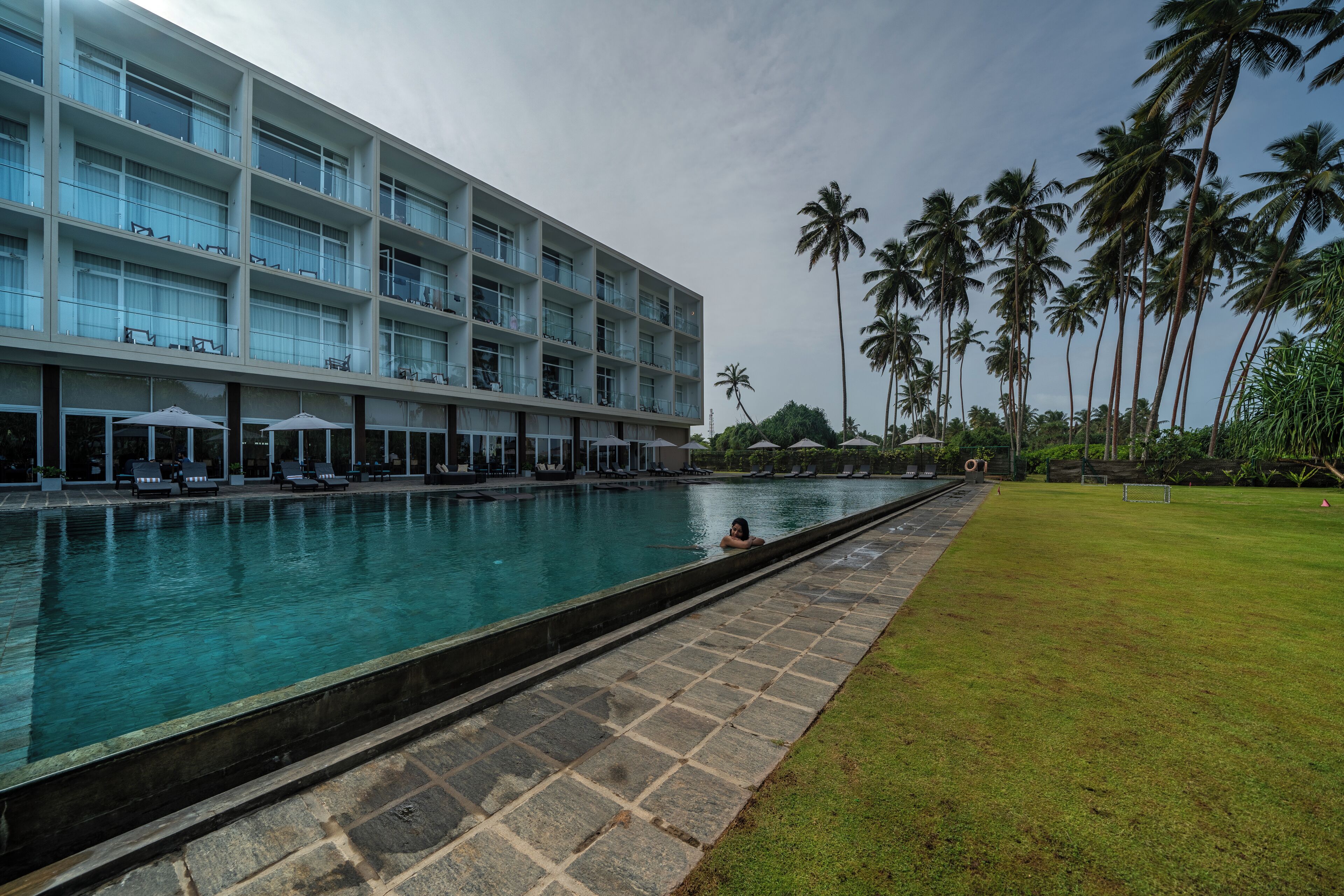 Un hôtel doté d’une piscine, d’une pelouse et de palmiers.