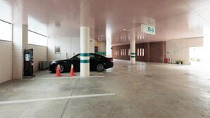 Un garaje para estacionamiento con un automóvil, una bomba de combustible y letreros de indicaciones.