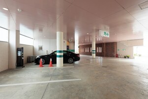 Un garaje para estacionamiento con un automóvil, una bomba de combustible y letreros de indicaciones.