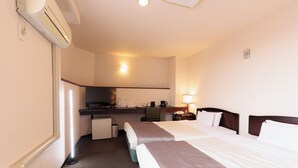 Habitación de hotel con dos camas, un escritorio, una silla, una kitchenette pequeña y un cubo de basura.