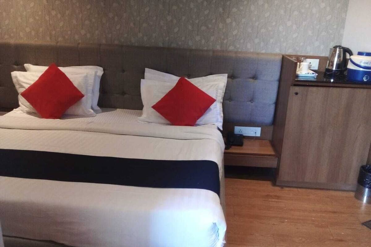 Een hotelkamer met een bed, twee kussens, een nachtkastje en een houten kast.