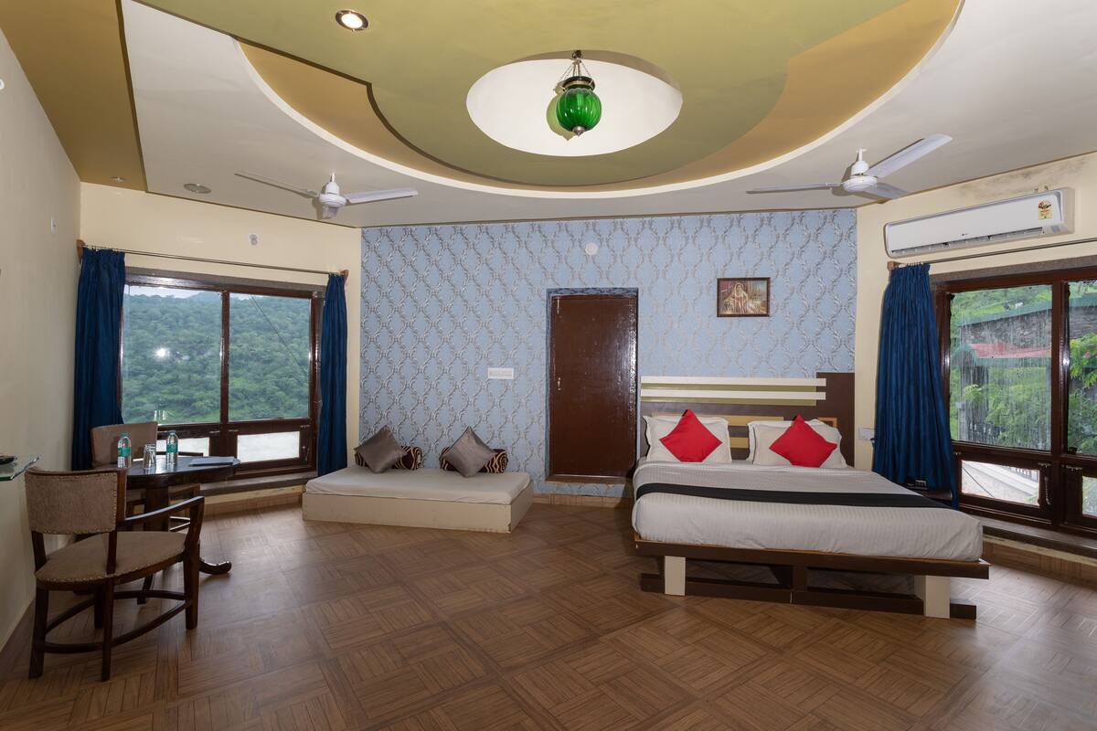 Een slaapkamer met een bed, een bureau, een stoel, een raam met uitzicht en een plafondventilator.