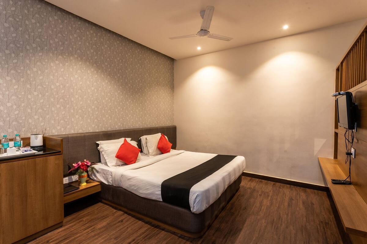 Een hotelkamer met een bed, nachtkastje en een aan de muur bevestigde televisie.