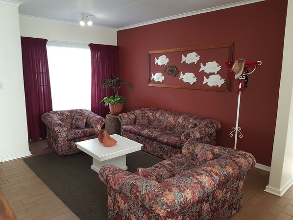 Una sala de estar con dos sofás estampados, una mesa de centro blanca y una planta en maceta.