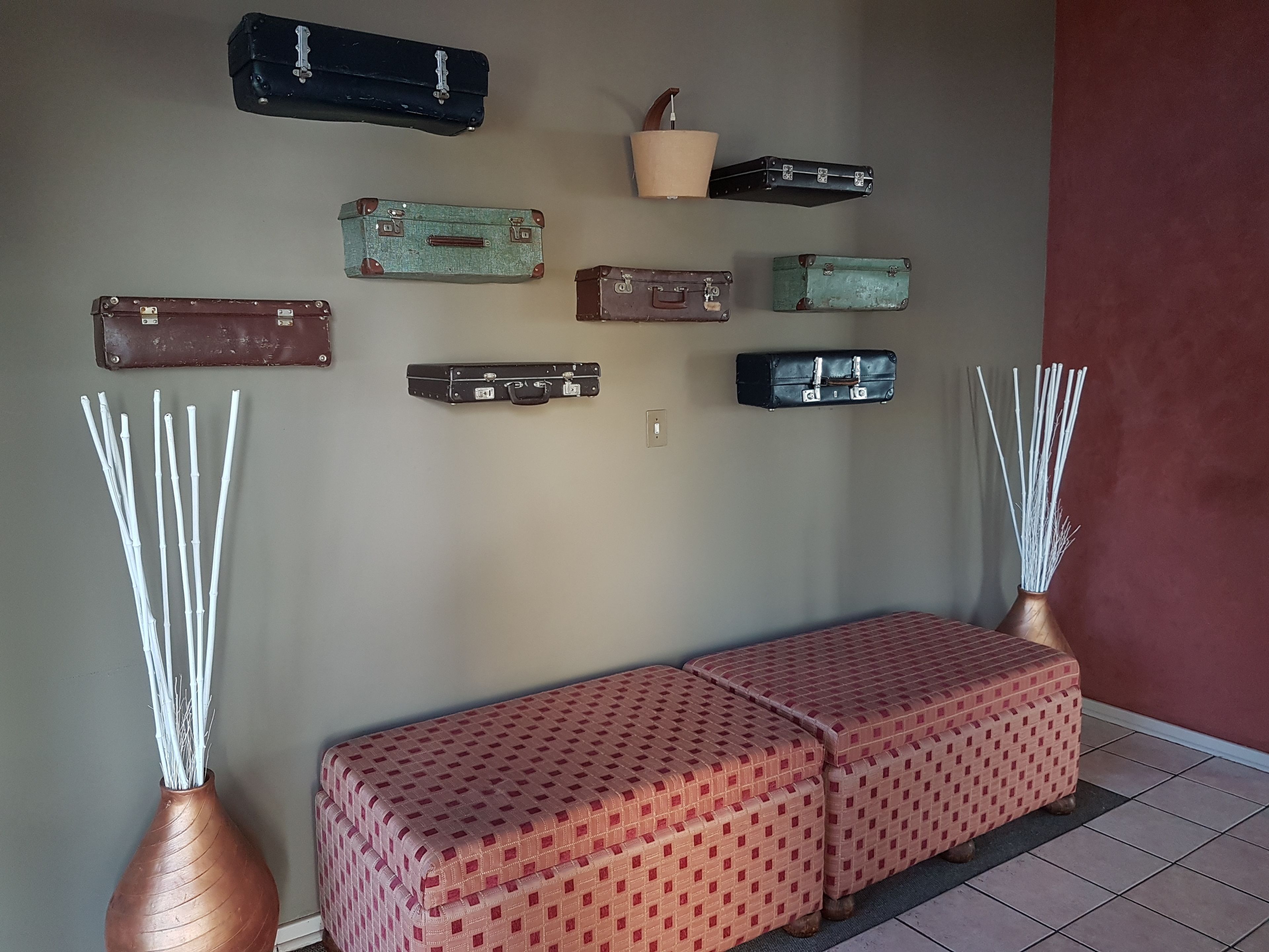 A wall with various vintage suitcases and a bench with a patterned cover.