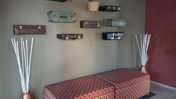 A wall with various vintage suitcases and a bench with a patterned cover.