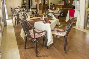 Enjoy meals in this inviting dining area with a round table, comfortable chairs, and a bar in the background.