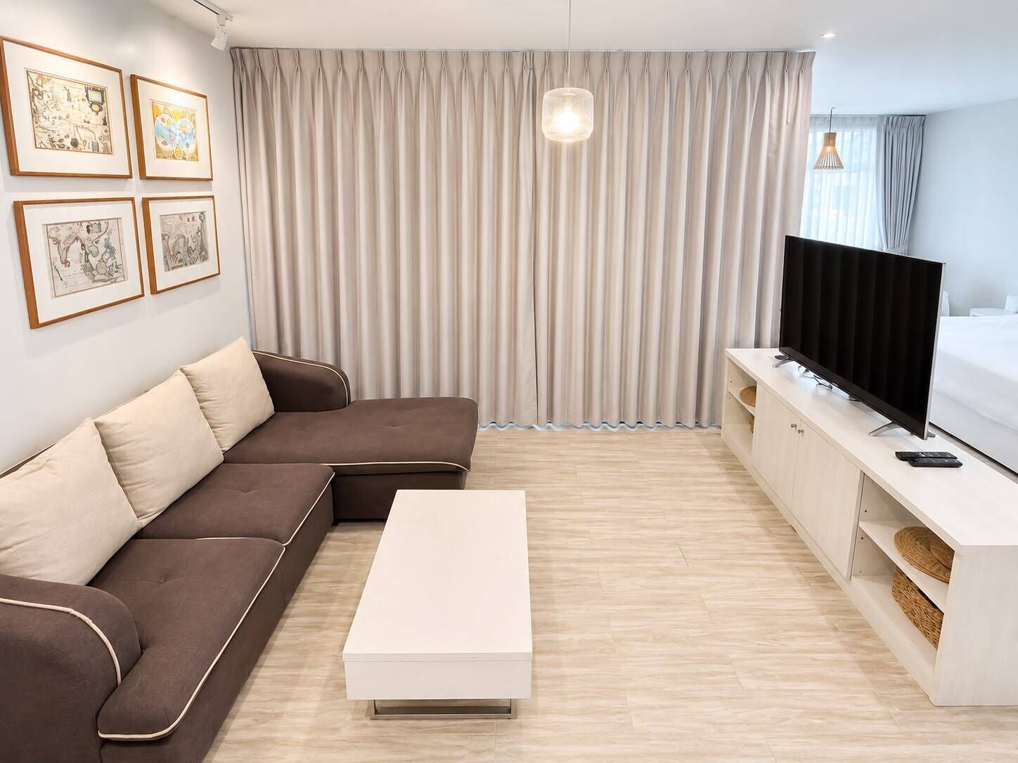 Una sala de estar moderna con un sofá modular, una mesa de centro blanca, un televisor de pantalla plana sobre un mueble blanco y obras de arte enmarcadas en la pared.