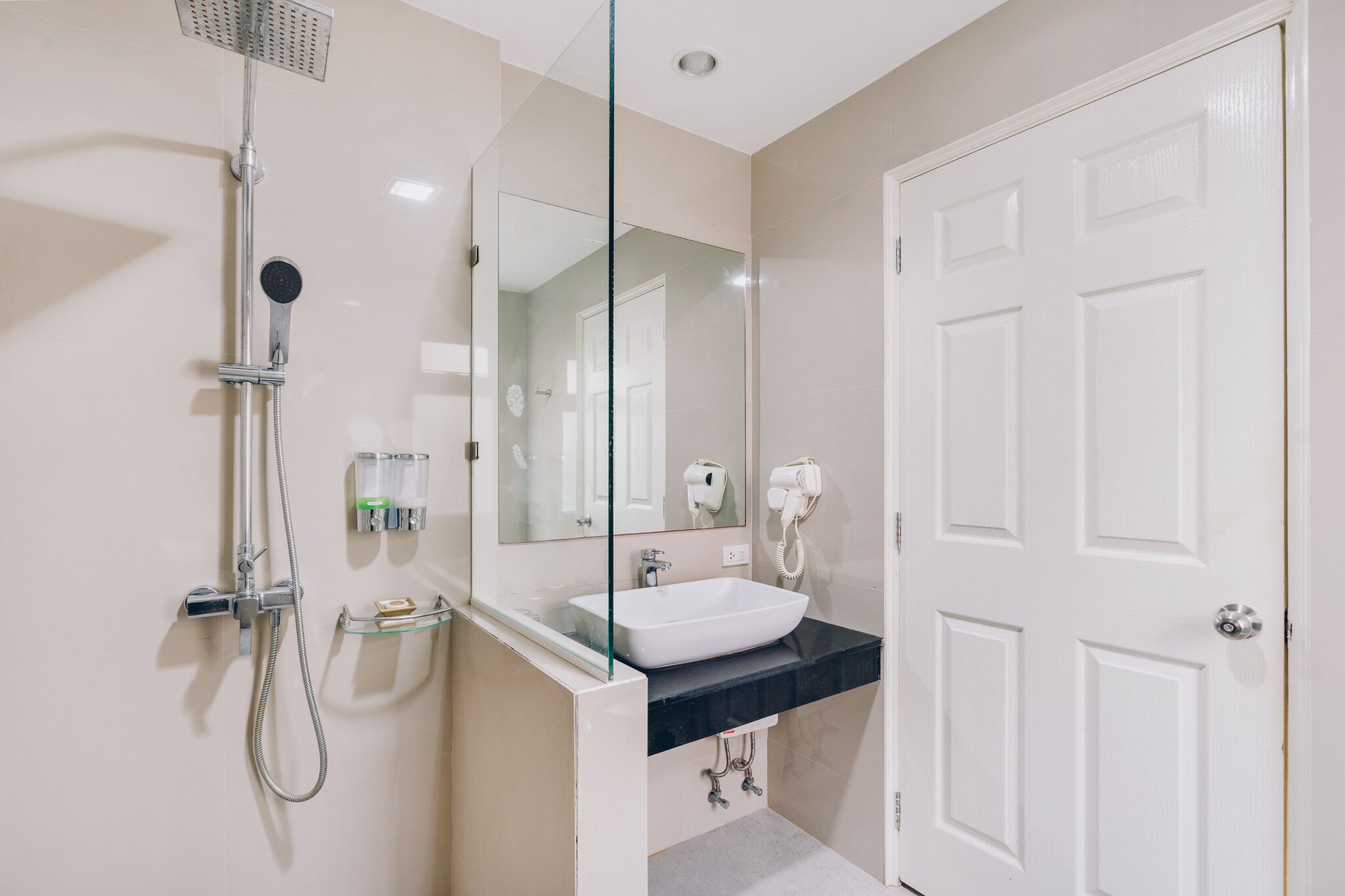A modern bathroom with a glass shower enclosure, a white sink, and a large mirror.