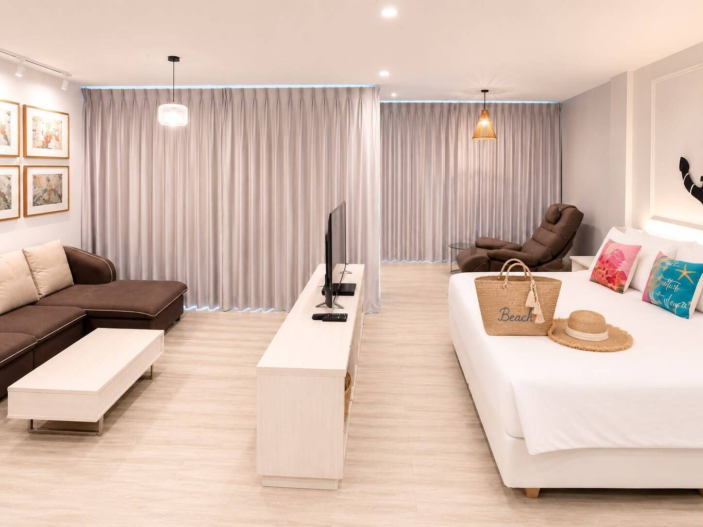 A modern hotel room with a sofa, a bed, a desk, a TV, and a chair.