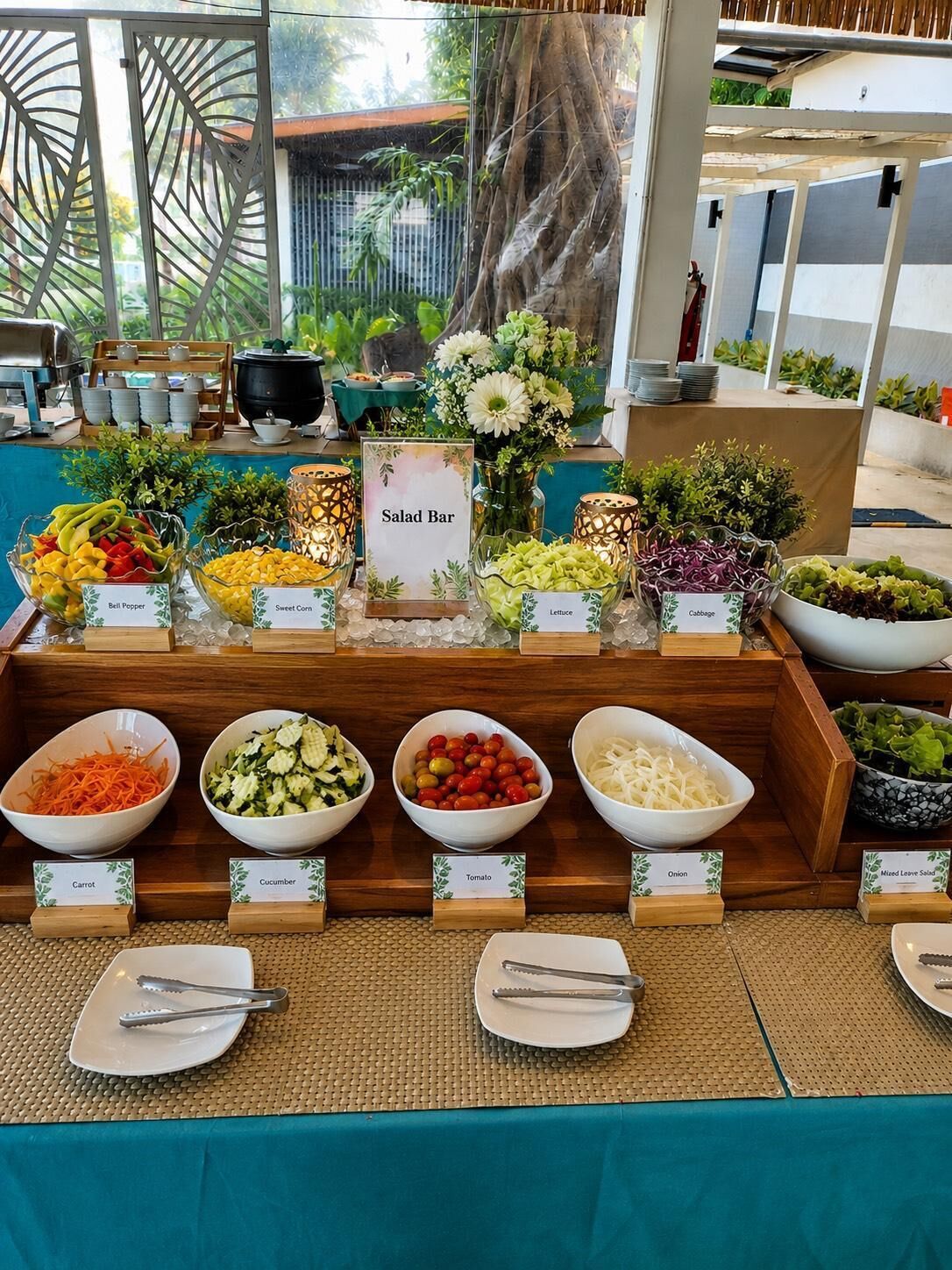 Un buffet avec des bols de légumes étiquetés et un panneau indiquant l’emplacement du bar à salades.