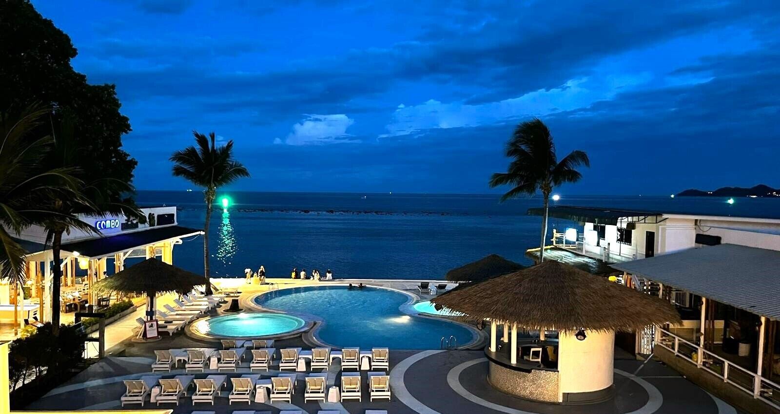 Un complexe hôtelier doté d’une piscine, de chaises longues et offrant une vue sur l’océan.
