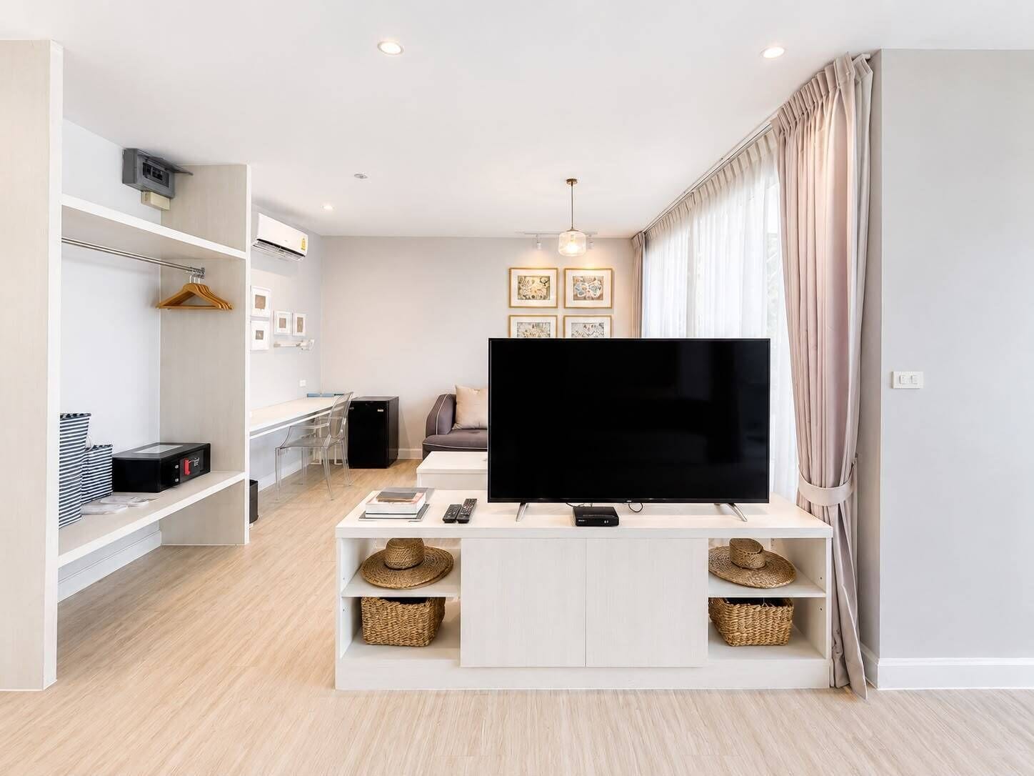 Een moderne woonkamer met een flatscreen televisie, een bank, een salontafel en een eethoek met een stoel en een kleine tafel.
