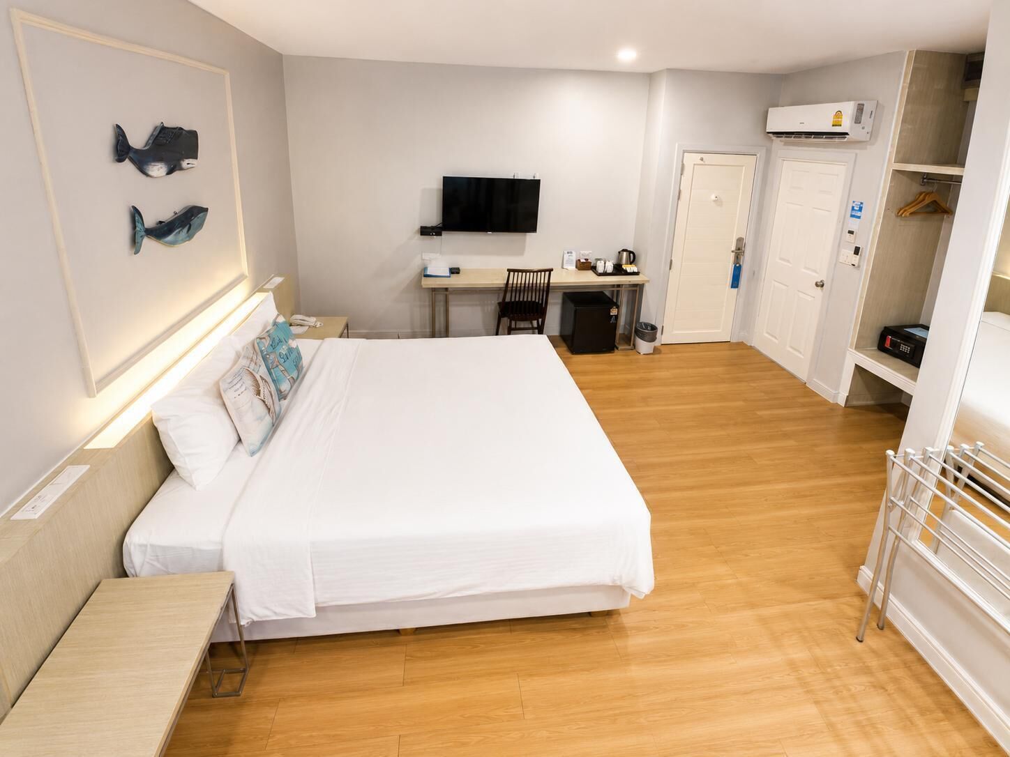Une chambre d’hôtel équipée d’un lit, d’un bureau, d’une télévision, d’une armoire et d’un espace douche.