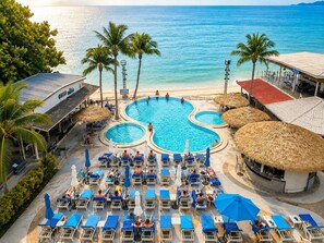 Un complexe hôtelier doté d’une grande piscine, de chaises longues et de palmiers.