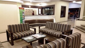 A lobby with striped sofas, a reception desk, and a staircase. - Hotel Panchavati Yatri (Nashik)