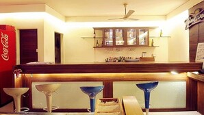 A bar area with a ceiling fan, a Coca-Cola refrigerator, and a Budweiser sign. - Hotel Panchavati Yatri (Nashik)